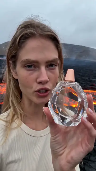 Creator toont een kristallen parfumflacon op vulkanisch gesteente met lava erachter