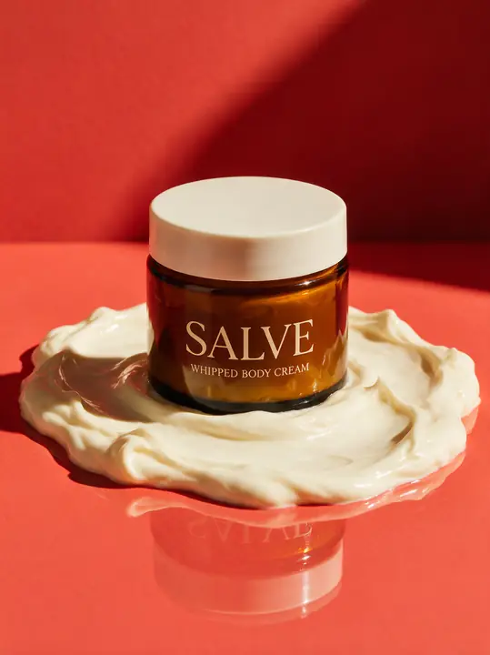 Amberkleurige pot op een wolk bodycreme tegen rood